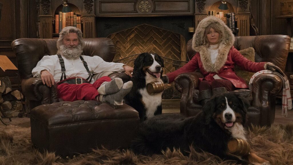 Santa and Mrs. Claus sitting in armchairs with dogs at their feet