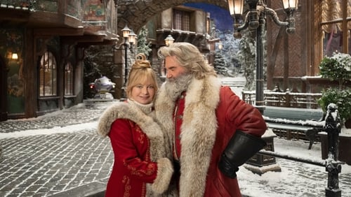 Santa and Mrs. Claus standing on a snowy street.