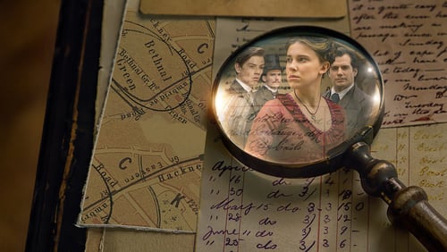 A magnifying glass on a table, the reflection of a young woman and three men can be seen in it