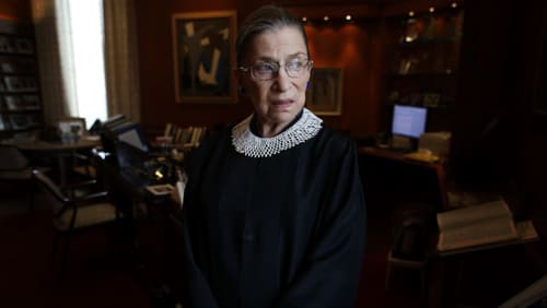 An elderly woman in a judges cloak standing in an office