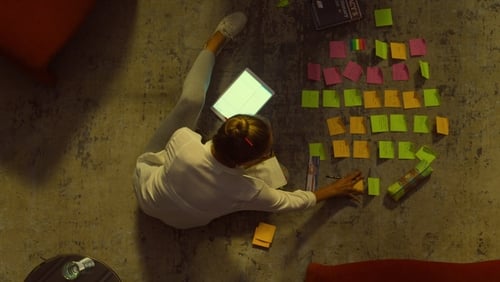woman sitting on a floor surrounded by post-it notes