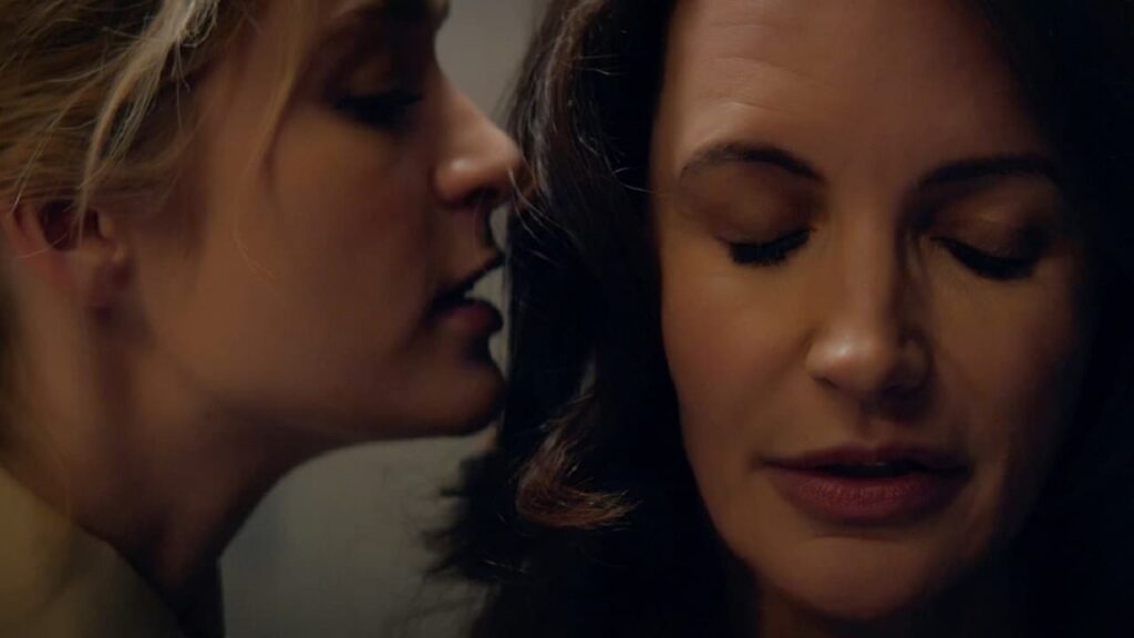 One woman whispering into another woman's ear