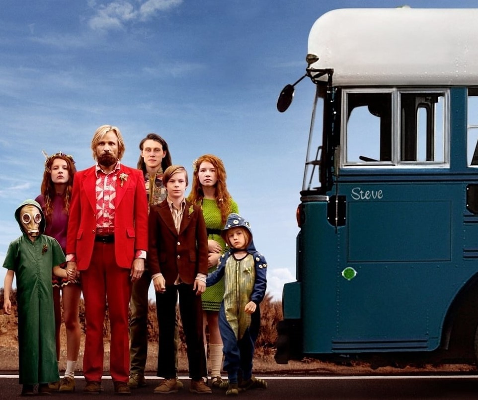 A father with six oddly dressed children standing in front of a bus