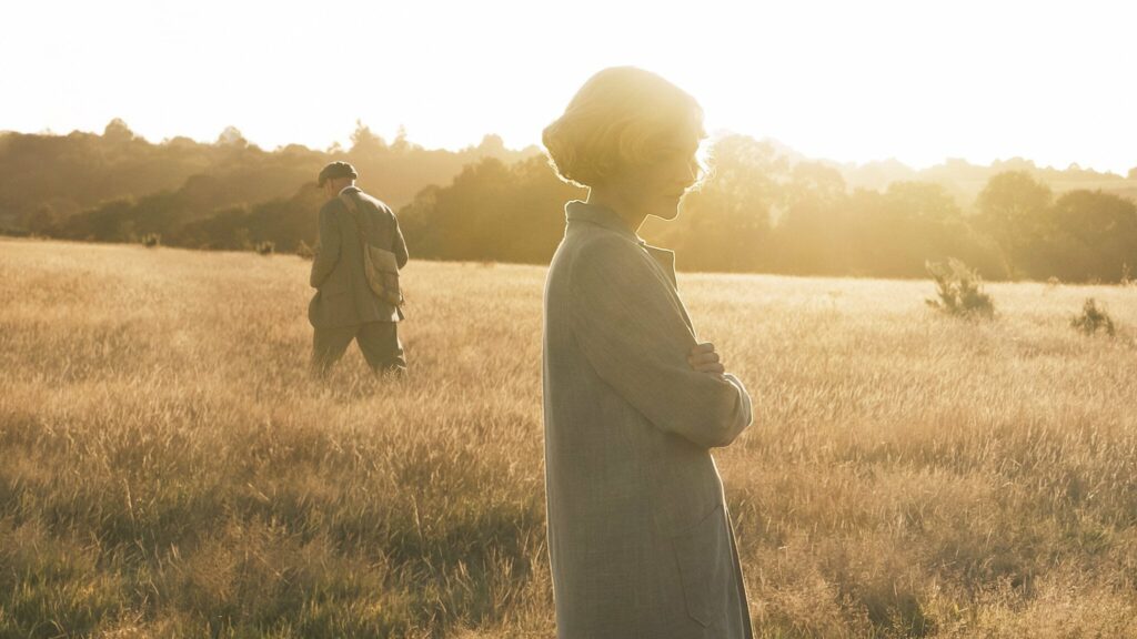 A woman standing in a field at sunset
