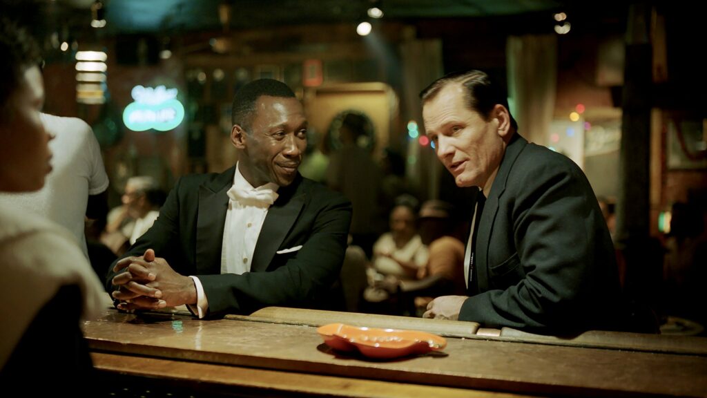 A black man and a white man sitting at a bar together