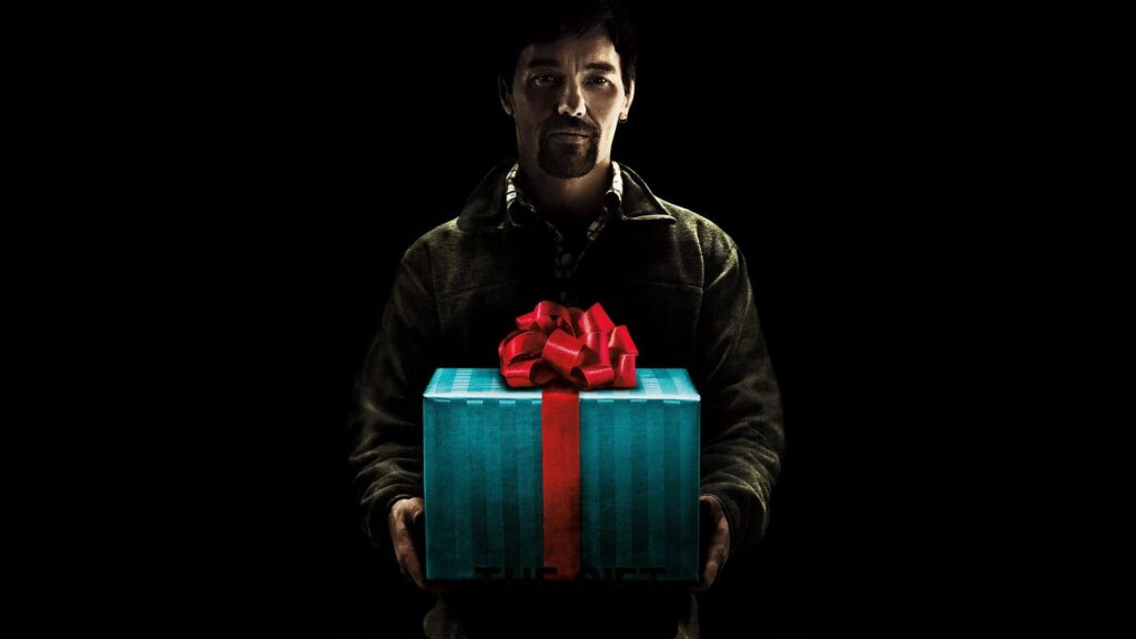 A man standing in a dark room holding a brightly wrapped gift box