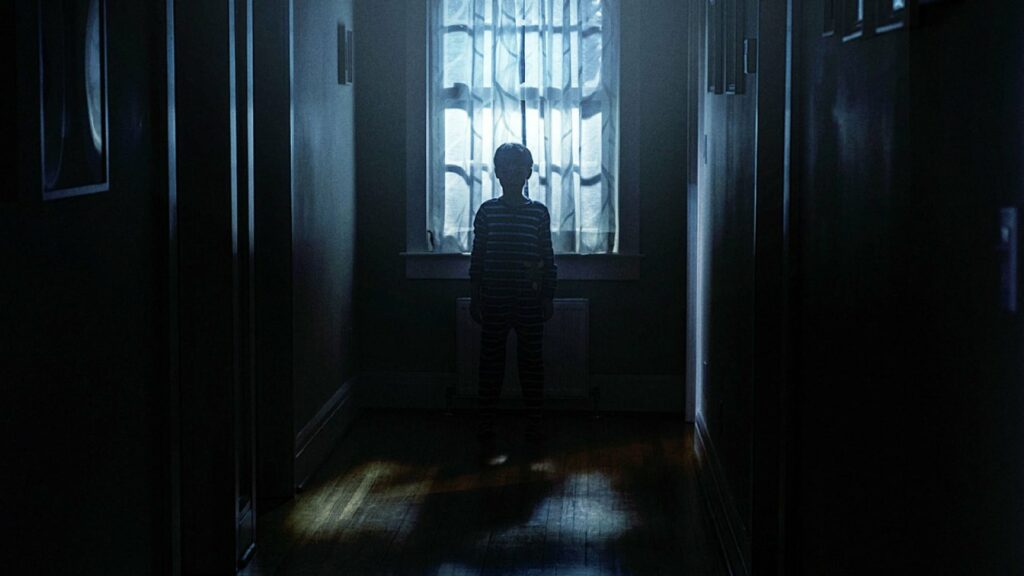 the silhouette of a boy standing in front of a window