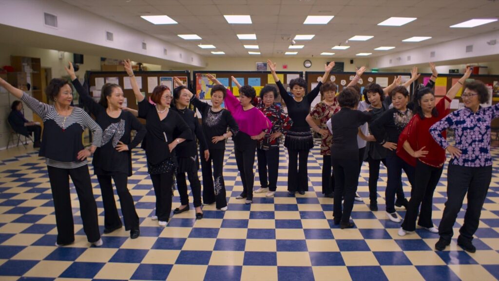 A semi-circle of Korean women standing together while practicing a dance routine