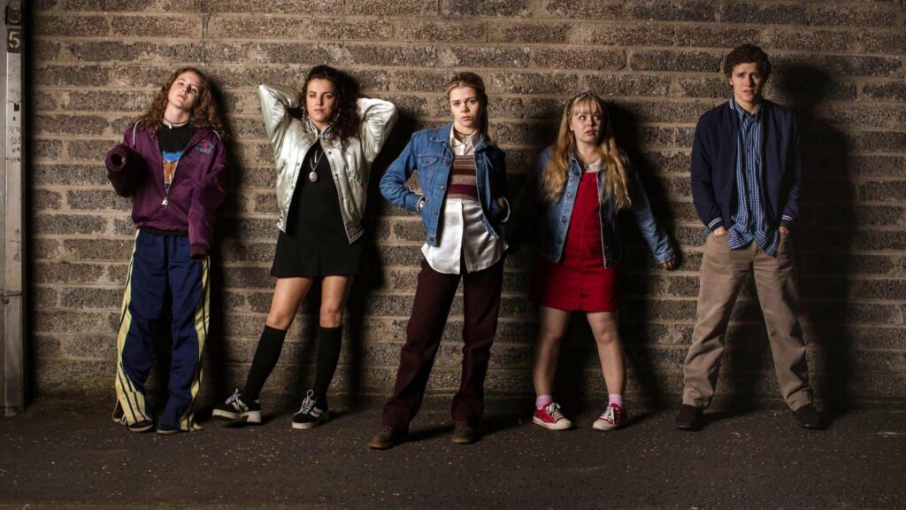 Four teen girls and a teen boy standing against an alley wall