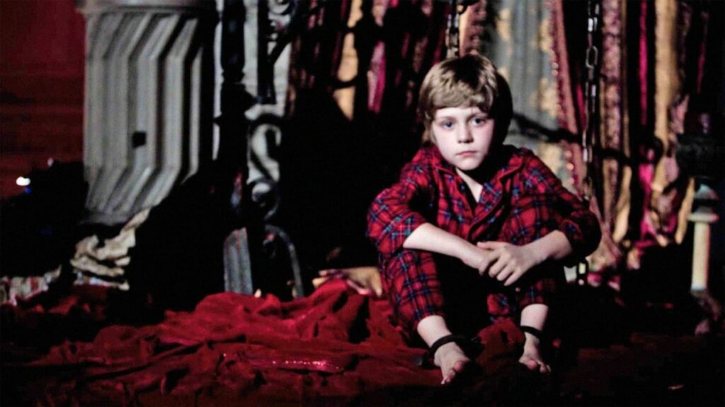 A young boy sitting on his bed
