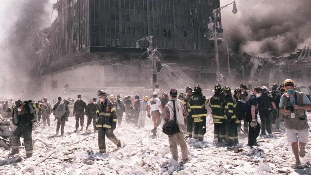 Fire Fighters and civilians standing in the rubble of fallen buildings